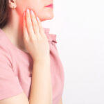 A brunette girl holds with her hand the jaw of a sick wisdom tooth. Painless Wisdom Tooth Removal.