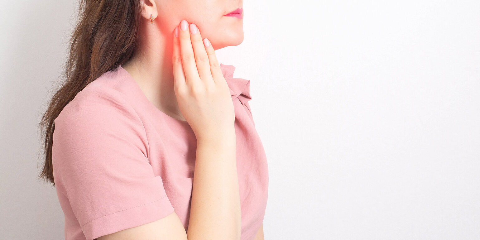 A brunette girl holds with her hand the jaw of a sick wisdom tooth. Painless Wisdom Tooth Removal.