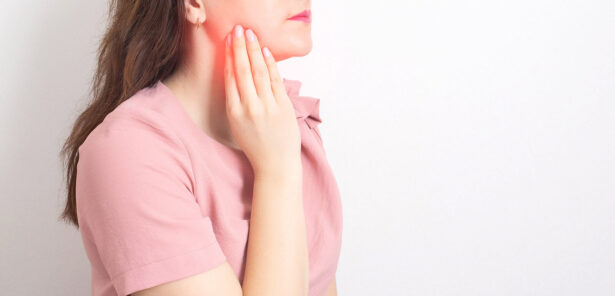 A brunette girl holds with her hand the jaw of a sick wisdom tooth. Painless Wisdom Tooth Removal.