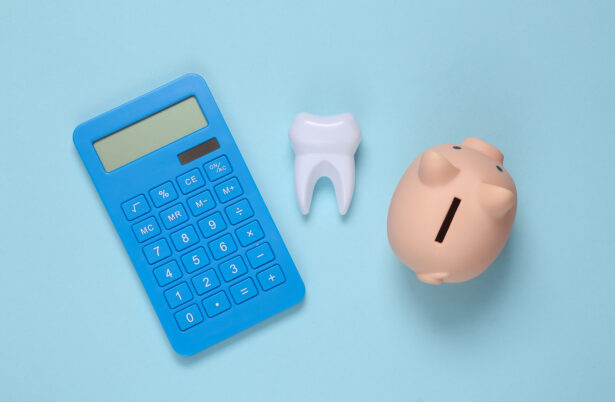 dental implants cost Dental treatment costs. Piggy bank, calculator and tooth on blue background. Top view