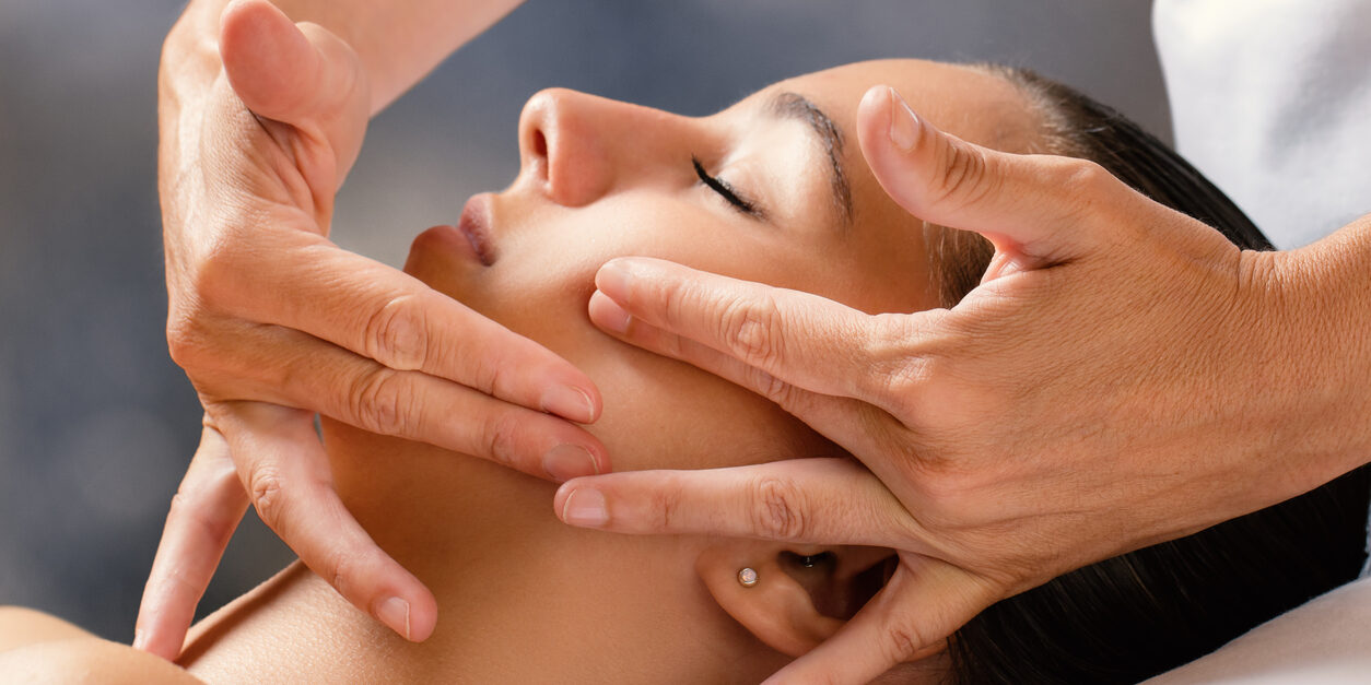 Therapist massaging female face.